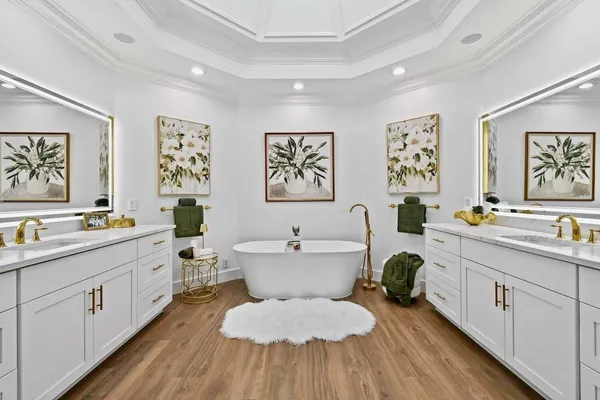 a spacious bathroom with a double vanity sink a mirror a bathtub and a window