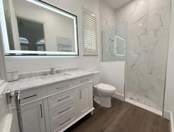 a bathroom with a granite countertop toilet a sink and a mirror