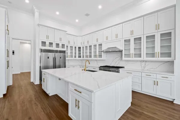 a kitchen that has a lot of white cabinets and stainless steel appliances