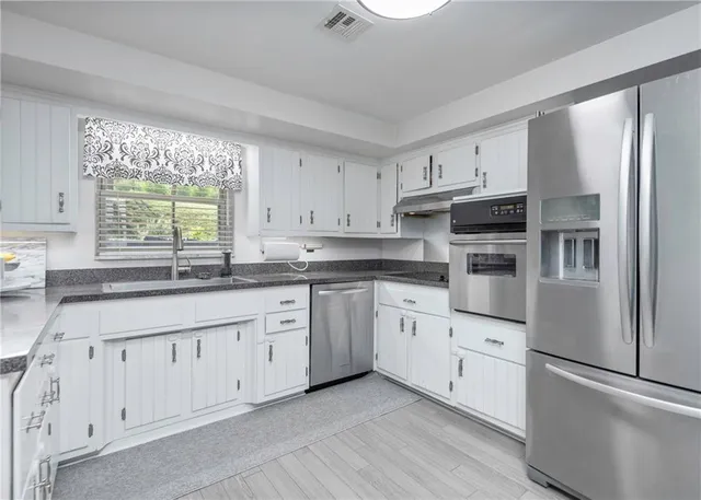 a kitchen with stainless steel appliances sink and white cabinets