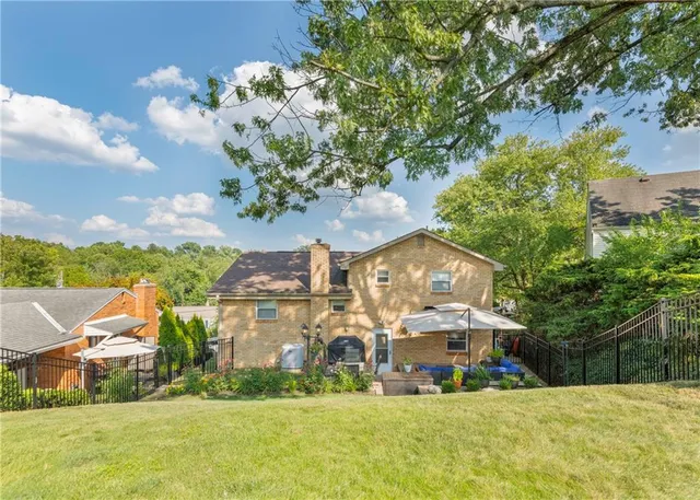 a view of a white house with a big yard and large trees