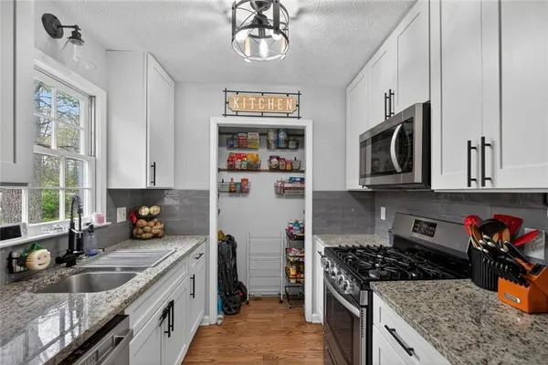 a kitchen with stainless steel appliances granite countertop a stove a sink and a microwave