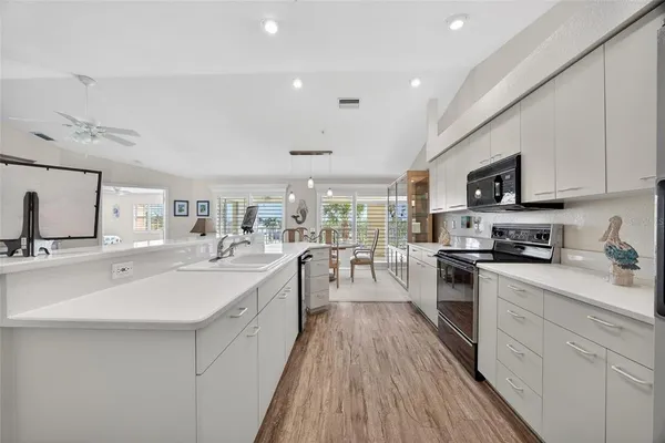 a kitchen with stainless steel appliances a sink dishwasher stove refrigerator and white cabinets with wooden floor