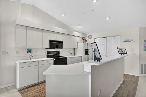 a view of a kitchen with kitchen island a sink wooden floor and a large window
