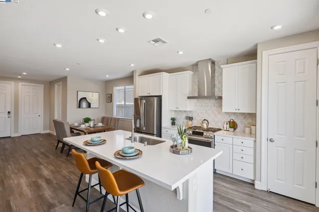a kitchen with a sink a stove a refrigerator and white cabinets with wooden floor