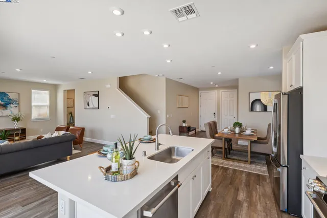 a living room with furniture kitchen view and a wooden floor