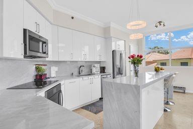 3700 South Ocean Boulevard, Unit 206 Highland Beach, FL 33487 - Photo 6 of 31 a kitchen with stainless steel appliances granite countertop a stove a sink dishwasher and white cabinets with wooden floor