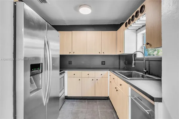 a kitchen with stainless steel appliances a sink a stove a microwave a refrigerator and cabinets