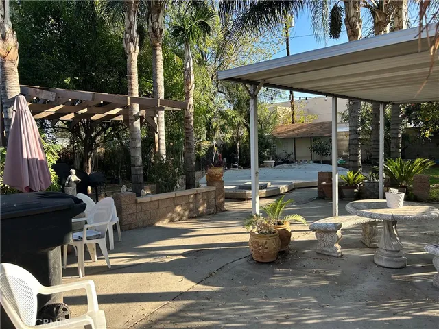 a view of a patio with dining table and chairs under an umbrella with a fire pit
