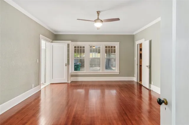 an empty room with wooden floor and a ceiling fan