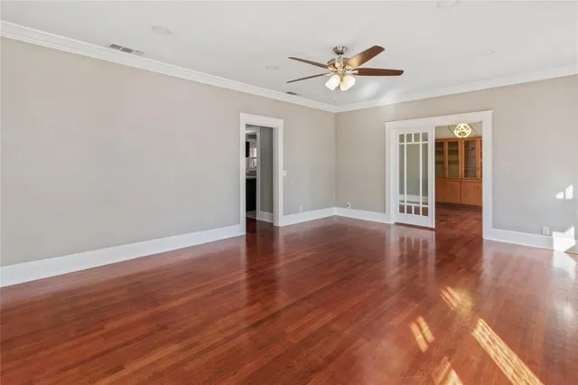a view of an empty room with wooden floor and a ceiling fan
