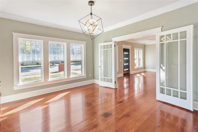 a view of a big room with wooden floor chandeliers and kitchen view