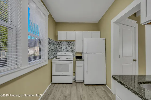a kitchen with a refrigerator a stove and wooden floor