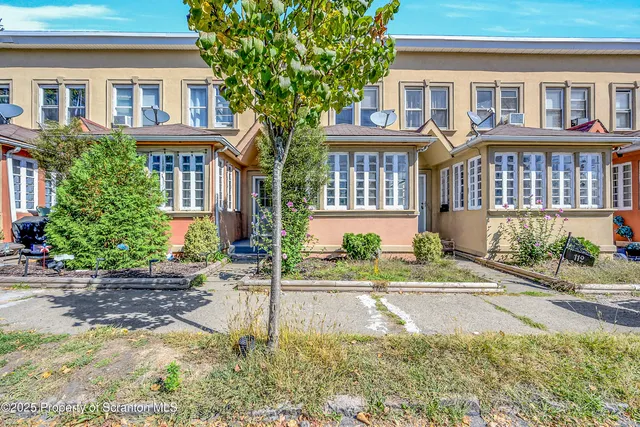 a front view of a house with a yard and potted plants