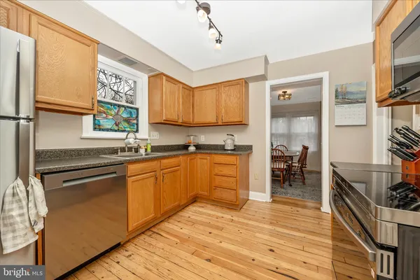 a kitchen with stainless steel appliances granite countertop a refrigerator a sink dishwasher a stove and white countertops with wooden floor