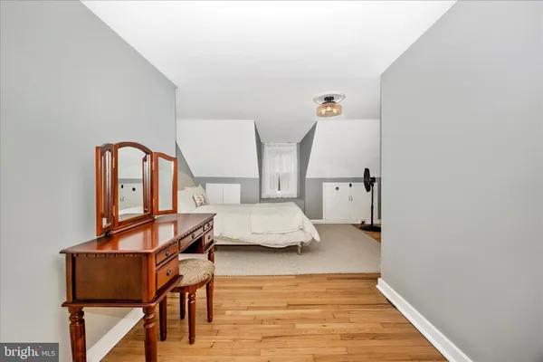 a bedroom with a bed and a dresser with wooden floor