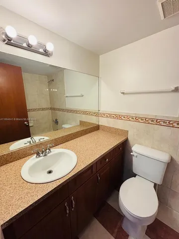 a bathroom with a granite countertop toilet sink and mirror