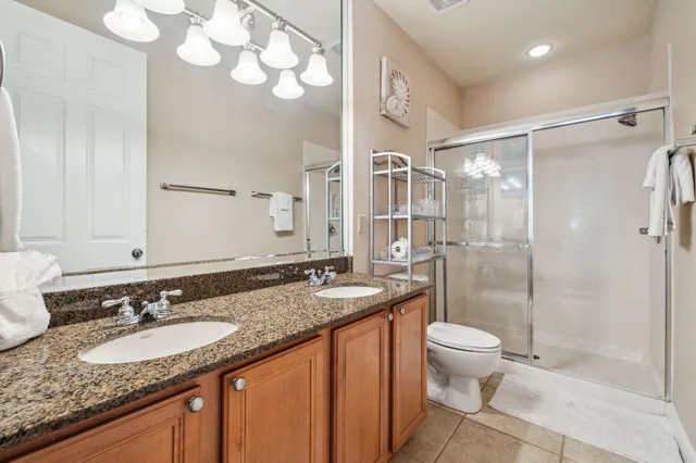 a bathroom with a granite countertop sink a toilet a mirror and shower