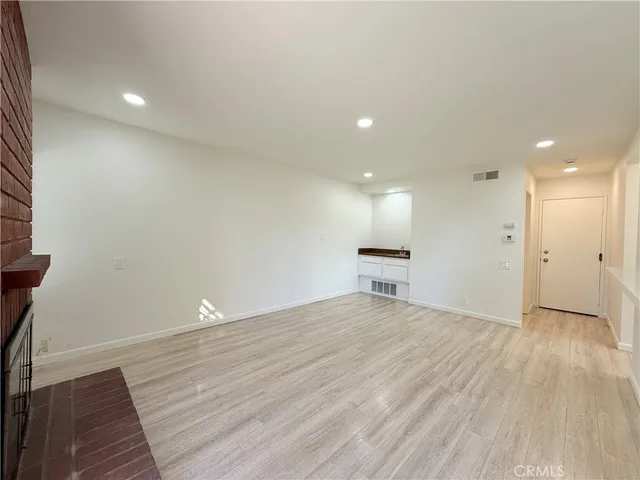 an empty room with wooden floor and fireplace