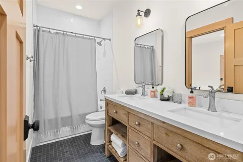 a bathroom with double vanity sink a mirror and a shower