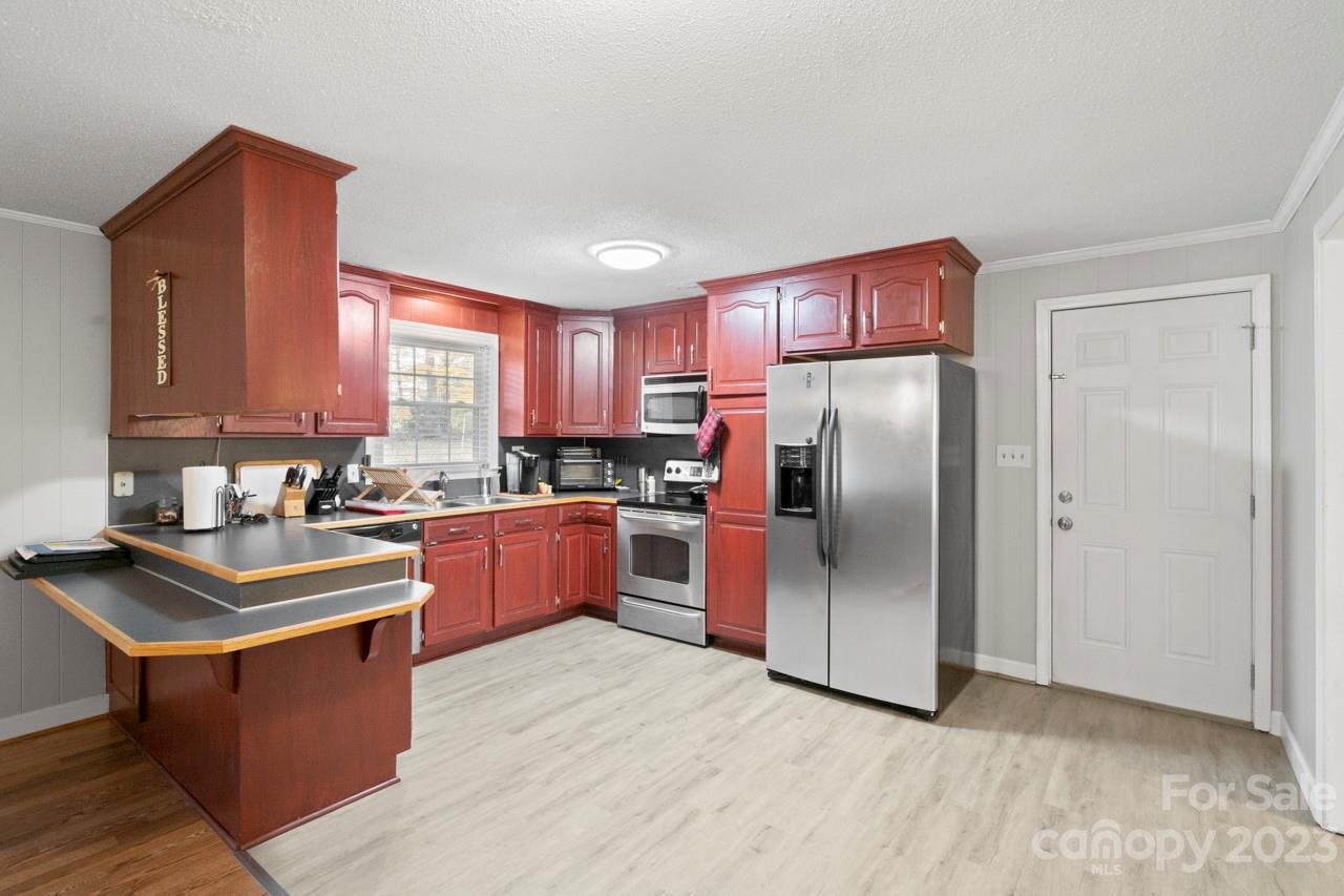 2656 Sandy Ford Road Newton, NC 28658 - Photo 8 of 34 a kitchen with stainless steel appliances granite countertop a refrigerator a sink dishwasher a stove with wooden cabinets and floor