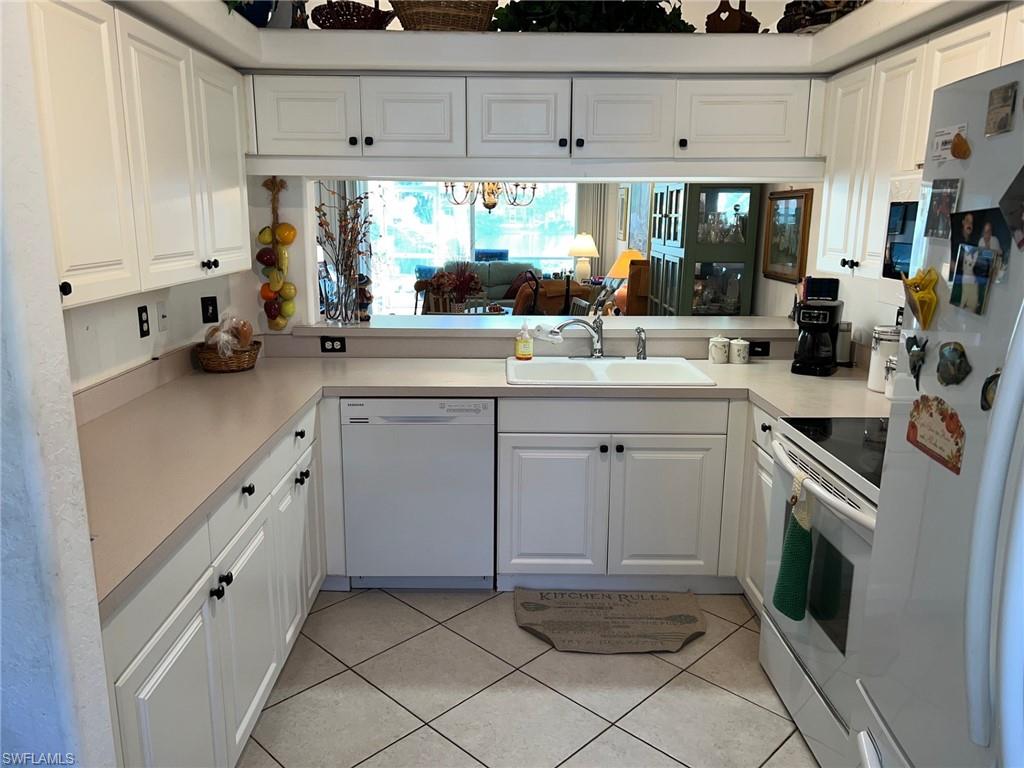 1220 Sarah Jean Circle, Unit L103 Naples, FL 34110 - Photo 4 of 23 a kitchen with white cabinets and white appliances