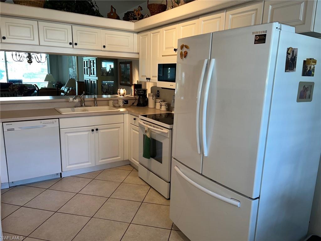 1220 Sarah Jean Circle, Unit L103 Naples, FL 34110 - Photo 5 of 23 a kitchen with stainless steel appliances a refrigerator sink and cabinets