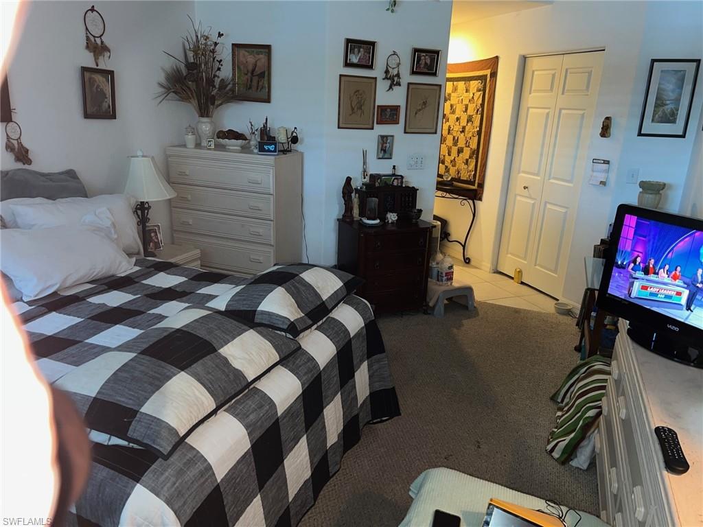 1220 Sarah Jean Circle, Unit L103 Naples, FL 34110 - Photo 10 of 23 a bedroom with a bed and flat screen tv