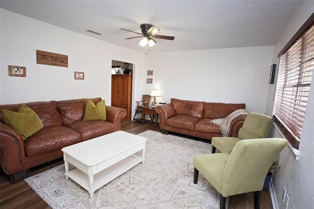 a living room with furniture a ceiling fan and a window