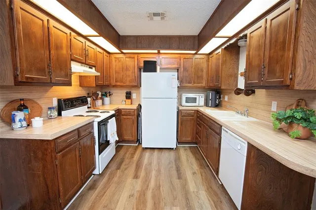 a kitchen with a sink a counter top space stainless steel appliances a window and cabinets