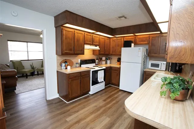 a kitchen with sink a refrigerator and wooden floor