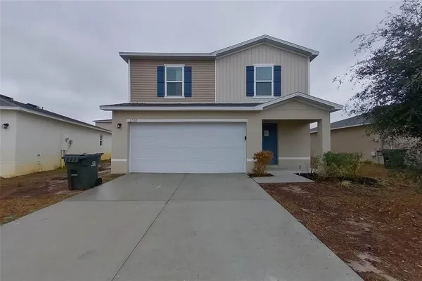 a front view of house with yard and trees in the background