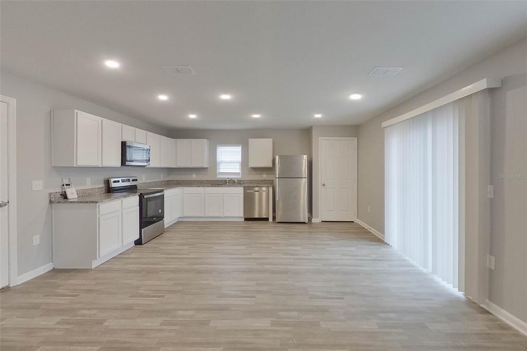 1709 Nebraska Loop Sumterville, FL 33585 - Photo 2 of 22 a large white kitchen with a white countertops and wooden cabinets
