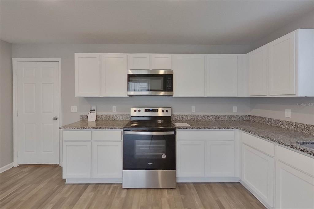 1709 Nebraska Loop Sumterville, FL 33585 - Photo 4 of 22 a kitchen with stainless steel appliances granite countertop a stove a sink and white cabinets