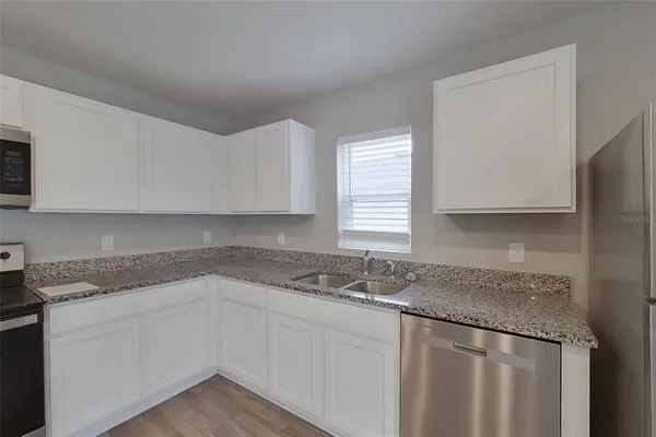 a kitchen with granite countertop cabinets sink and window