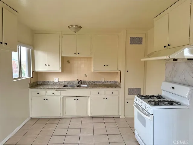 a kitchen with granite countertop a stove sink and cabinets