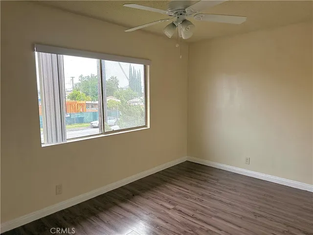 an empty room with wooden floor fan and windows