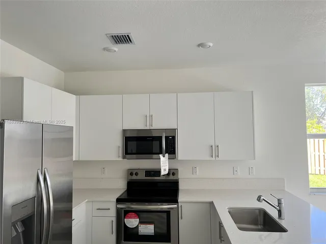 a kitchen with white cabinets and stainless steel appliances