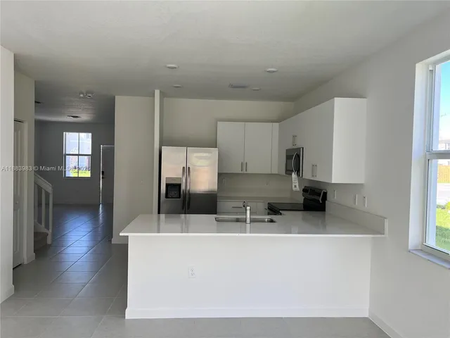a kitchen with stainless steel appliances a refrigerator a sink a stove and white cabinets