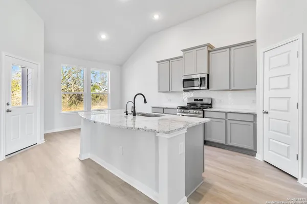a kitchen with kitchen island white cabinets a sink a window and stainless steel appliances