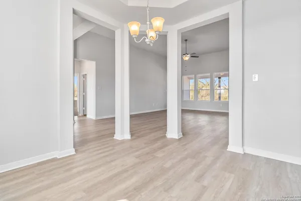 a view of a hallway with wooden floor and chandelier