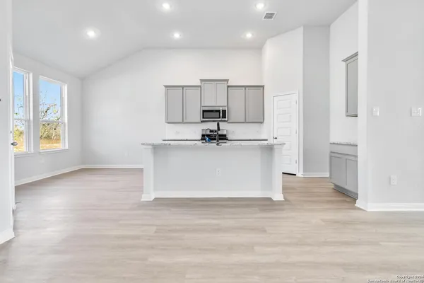 a view of kitchen with stainless steel appliances granite countertop a stove a sink dishwasher and a refrigerator with wooden floor
