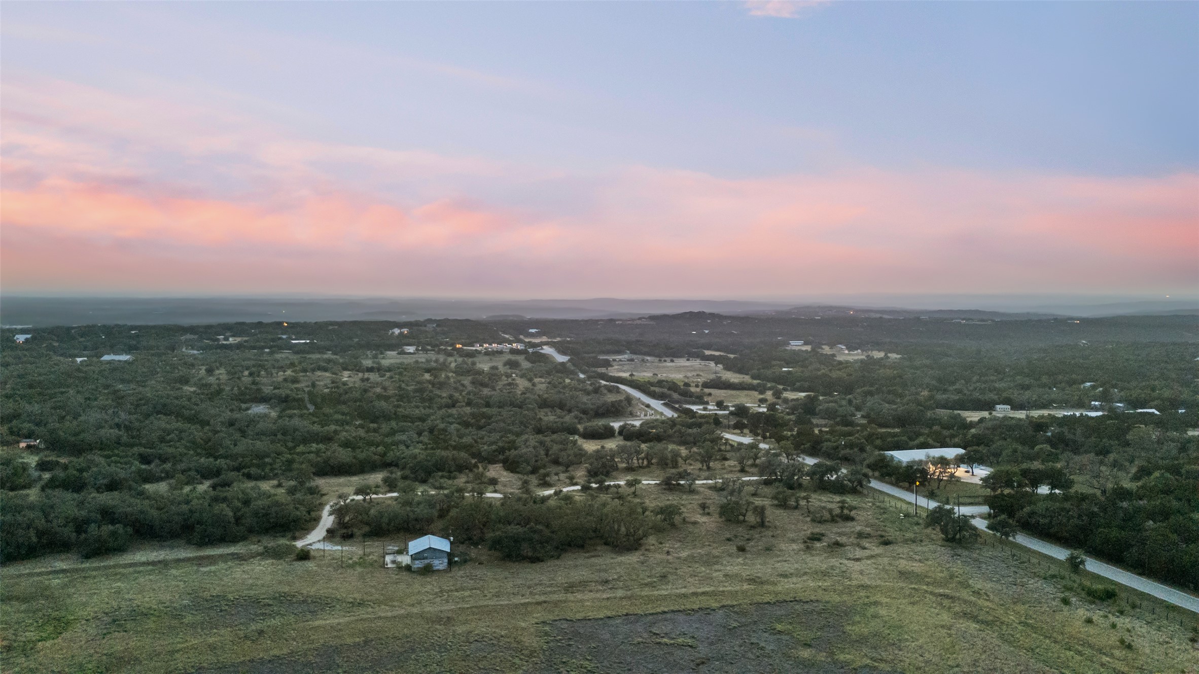 Lot 2 West Fitzhugh Road Dripping Springs, TX 78620 - Photo 3 of 9 Distant hill country ridges stretch toward a colorful horizon under soft twilight skies.