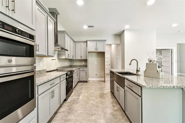 a large kitchen with stainless steel appliances granite countertop a stove top oven a sink and dishwasher