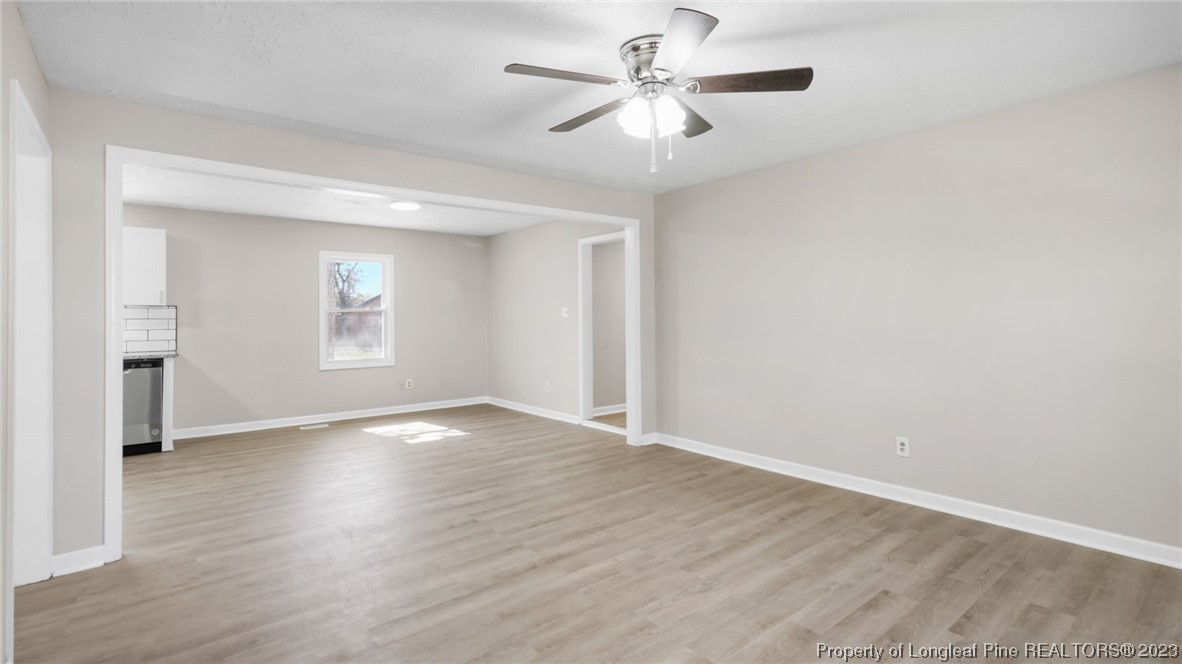 6114 Sandy Creek Road Stedman, NC 28391 - Photo 5 of 34 an empty room with wooden floor chandelier fan and windows
