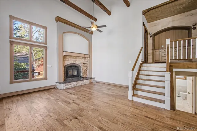 a view of an empty room with wooden floor fireplace and a window