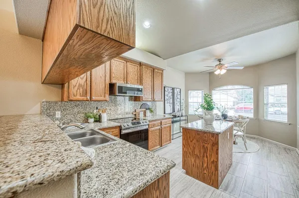 a kitchen with stainless steel appliances granite countertop sink stove refrigerator and cabinets
