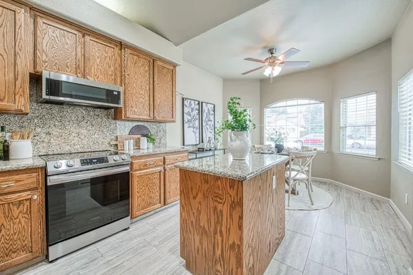 a kitchen with stainless steel appliances granite countertop a stove a sink dishwasher and a microwave oven with wooden floor