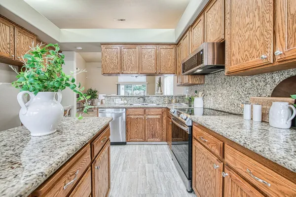 a kitchen with stainless steel appliances granite countertop a sink a stove and a wooden cabinets