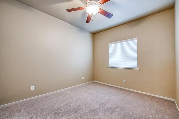 an empty room with a chandelier fan and windows